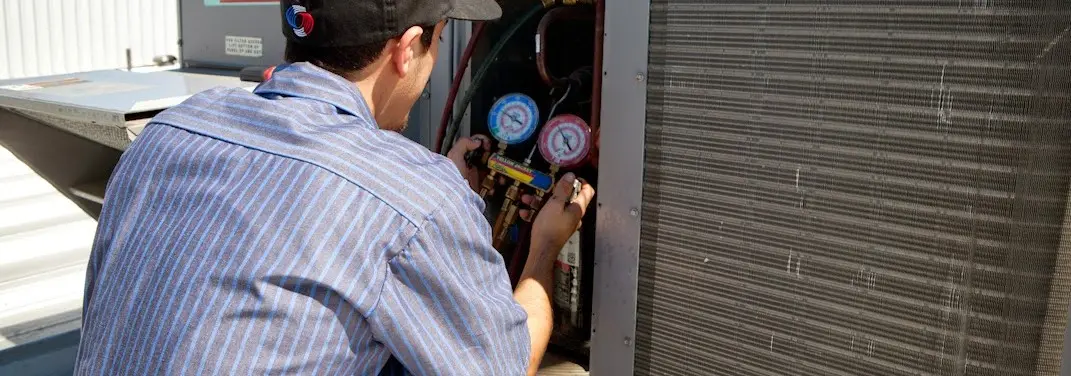 HVAC technician servicing a condenser unit in Halls