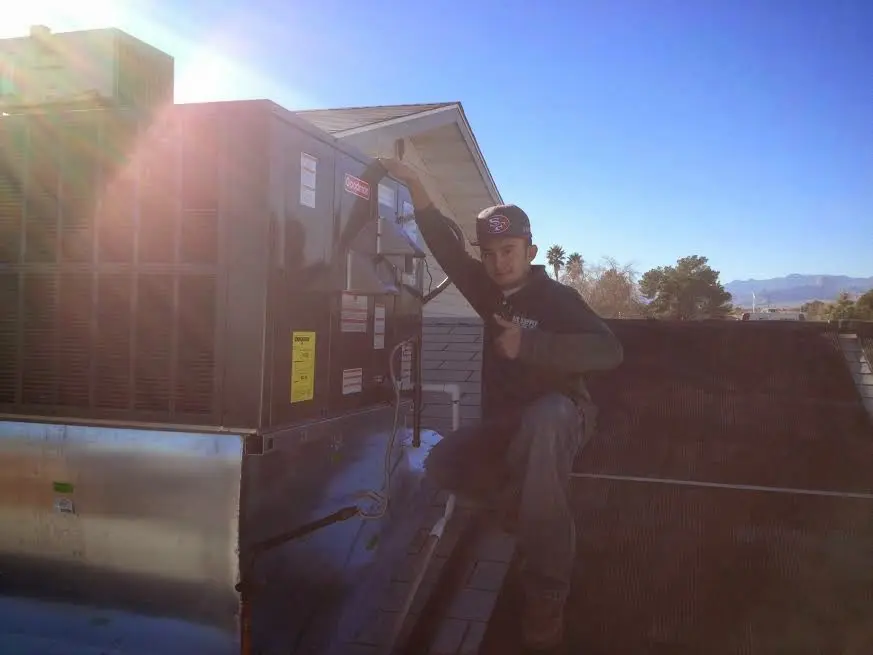 HVAC technician performing HVAC Inspection on a rooftop unit in Halls